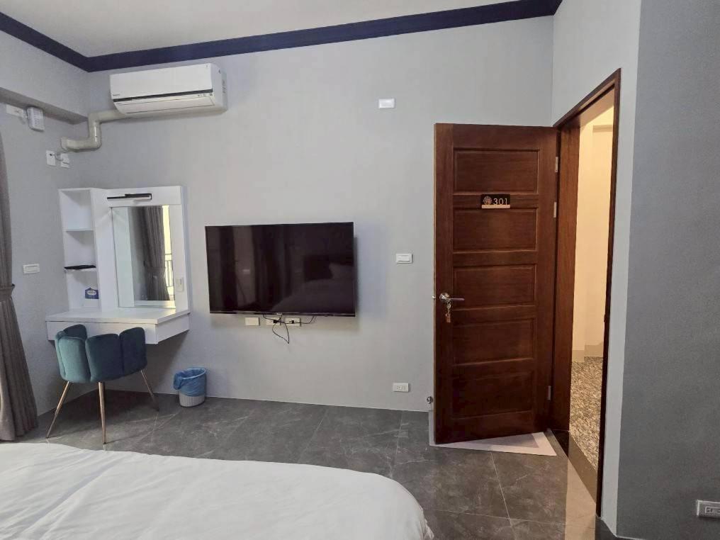 東港鎮にある東港包棟 悠舍民宿のベッドルーム1室(ベッド1台、壁掛けテレビ付)