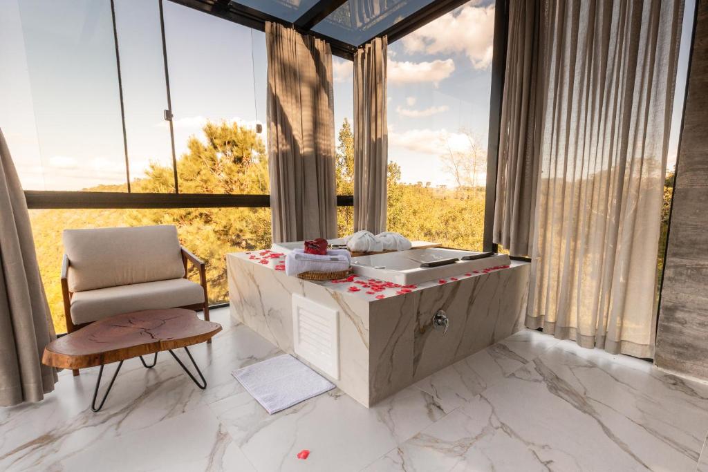 a bathroom with a sink and a chair and large windows at Cabana Morada nas Nuvens in Pinto Bandeira