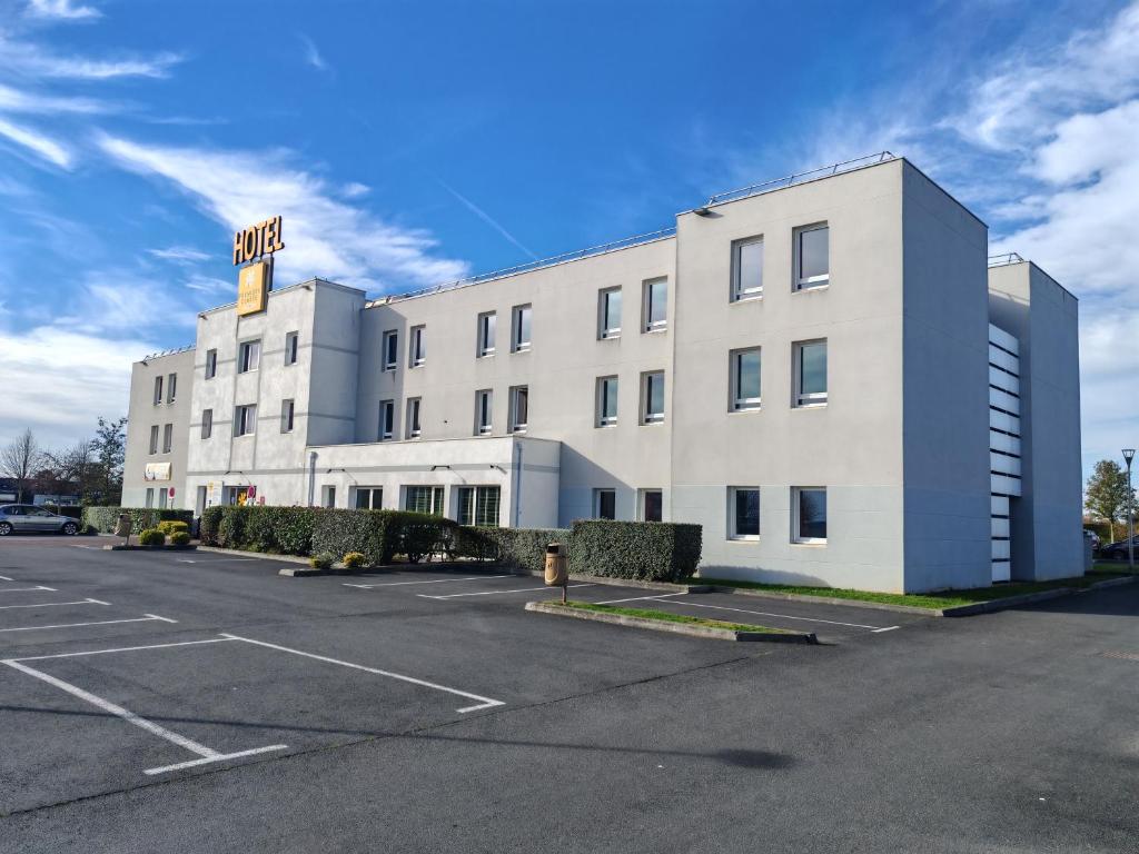a white building with a parking lot in front of it at Premiere Classe Caen Nord - Mémorial in Caen