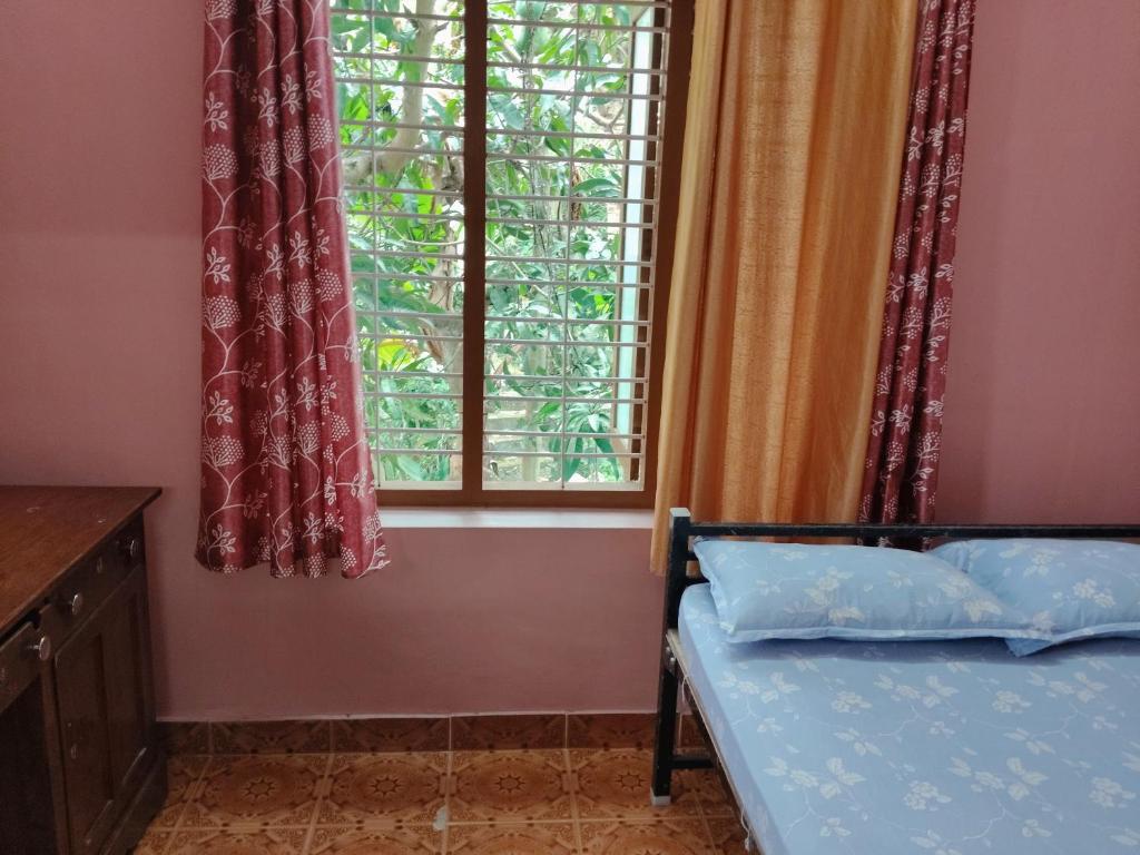 a bedroom with a bed and a window at Kashi East Valley in Varkala
