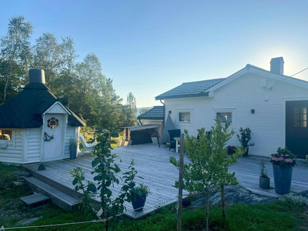 un patio trasero con terraza de madera junto a una casa en White Cabin With Jacuzzi And Fjord Views, en Bernes