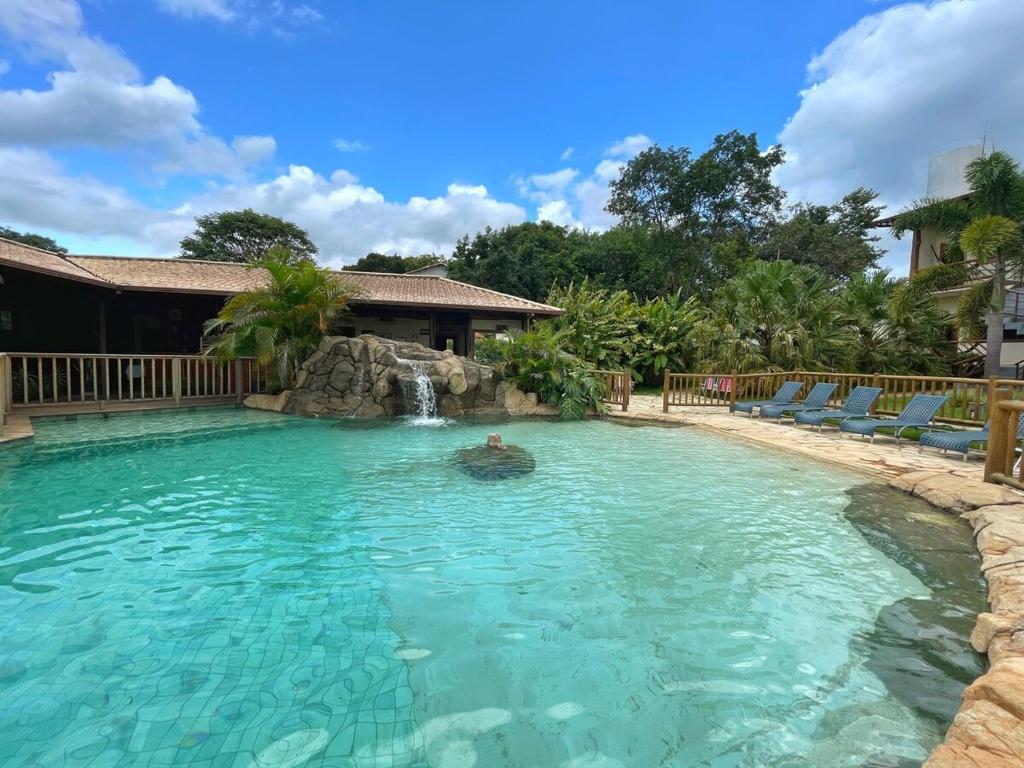 una piscina con cascata e una persona in acqua di Casa das Palmeiras - Charm and Comfort in the Center a Alto Paraíso de Goiás