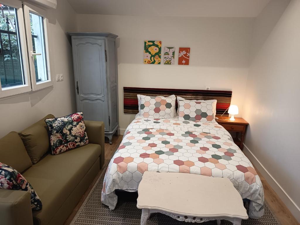 a bedroom with a bed and a couch at studio maisonette in Eysines