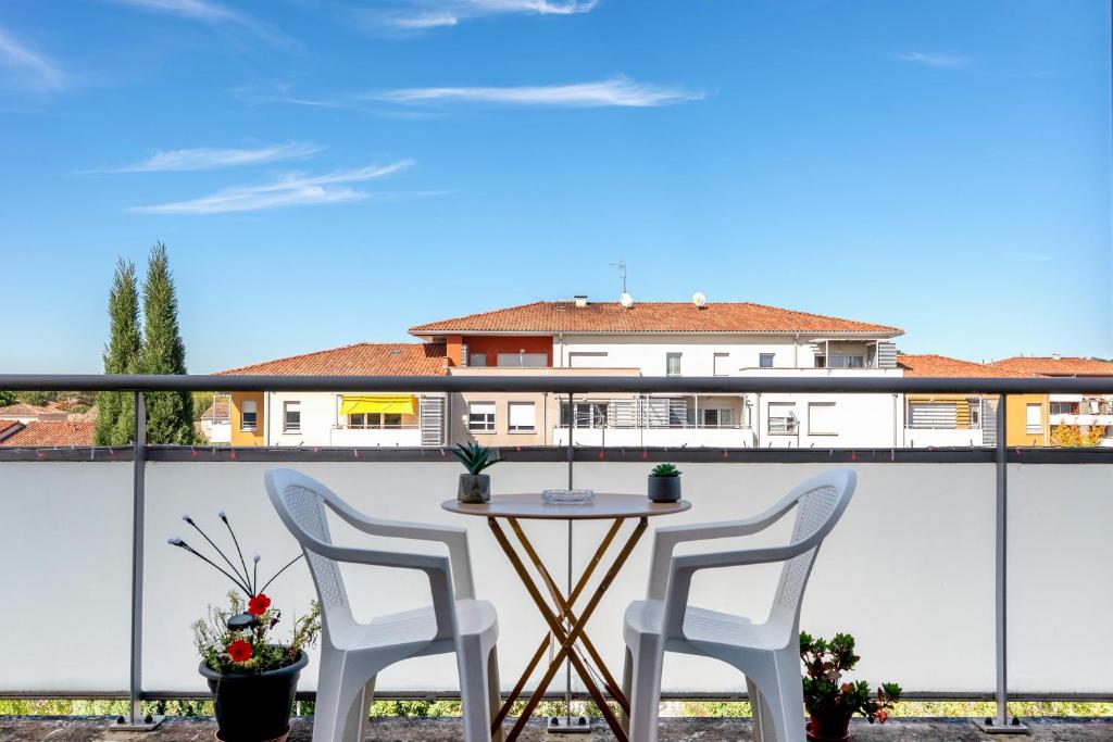 a table and two chairs on a balcony with a building at Ô Cocon Paisible - WiFi, Calme, Smart TV, Parking - A 2min du Campus TBS in Quint-Fonsegrives