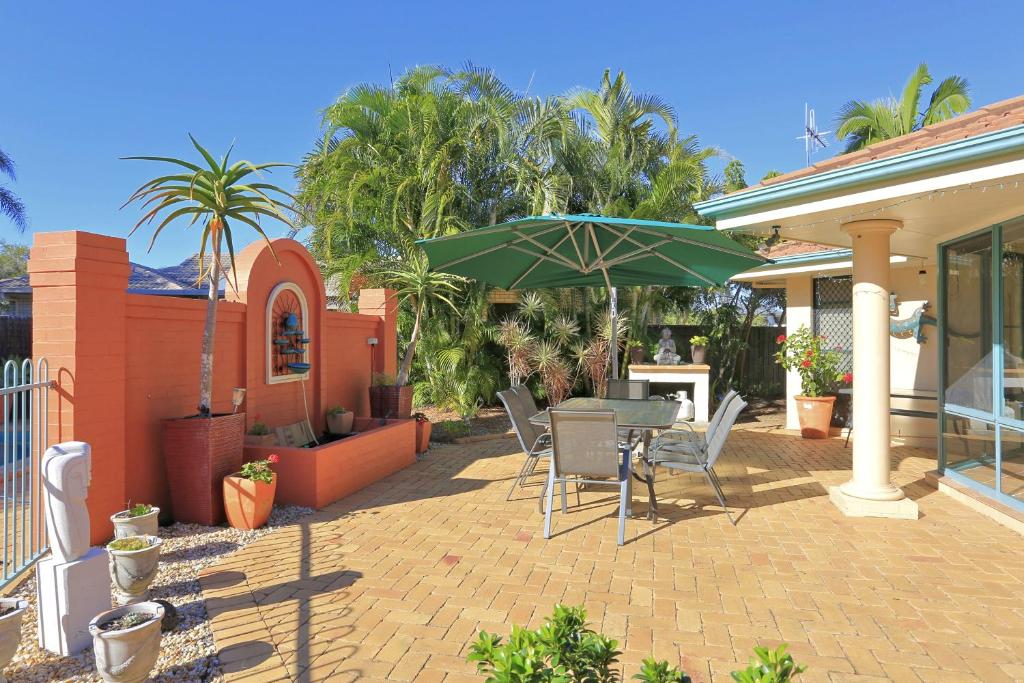 eine Terrasse mit einem Tisch, Stühlen und einem Sonnenschirm in der Unterkunft Golden Cane Bed & Breakfast in Bargara