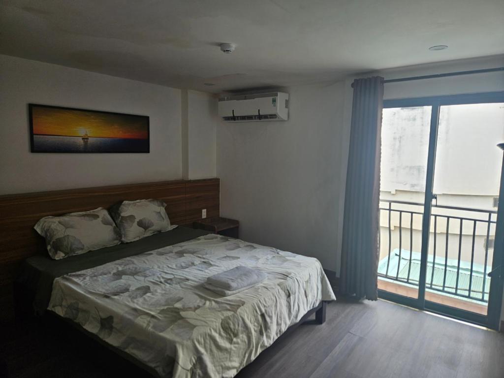 a bedroom with a bed and a large window at SAM Hotel and Apartment in Da Nang