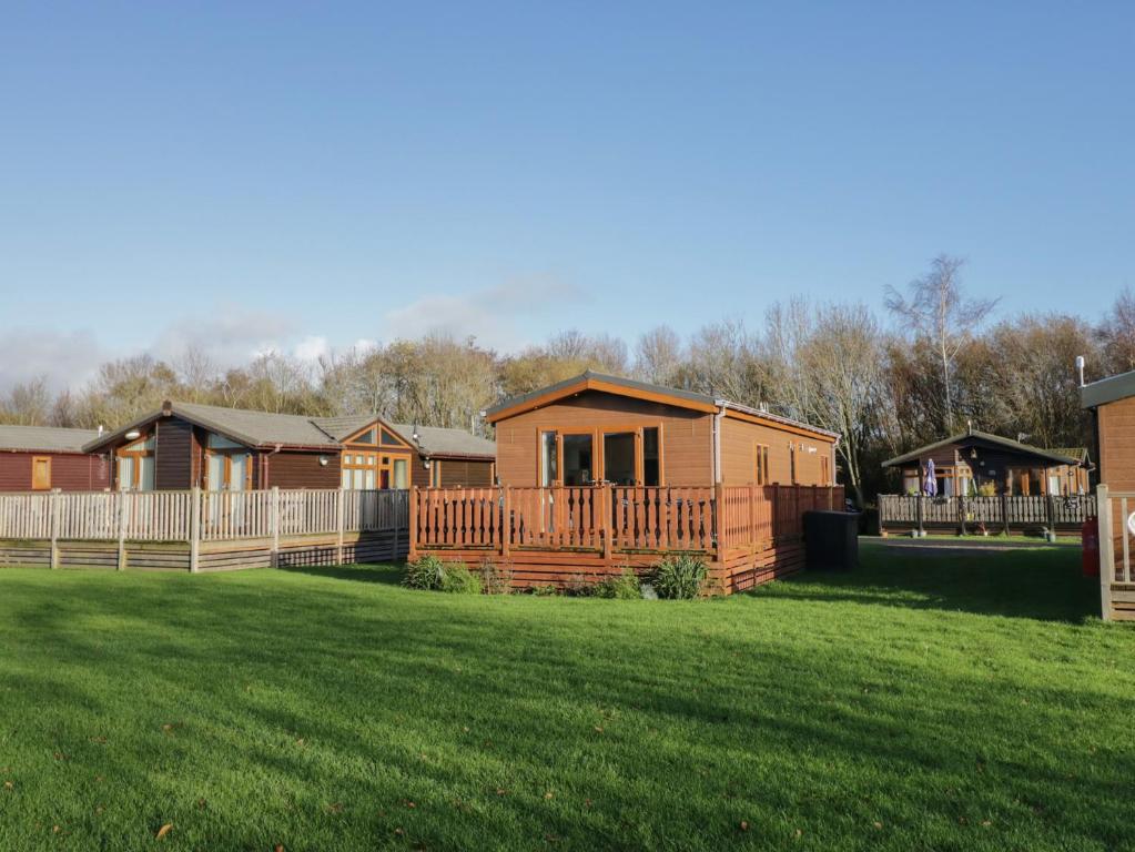 a row of houses in a yard with a grass field at Bluebell Lodge in Carnforth