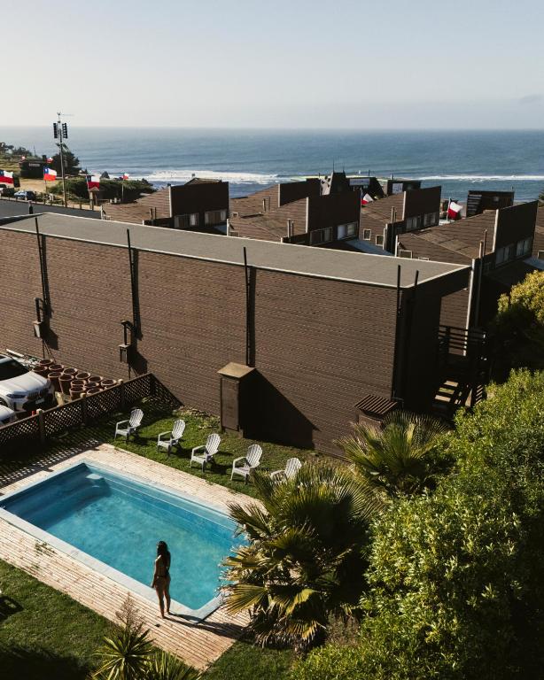 a woman standing next to a swimming pool next to the ocean at Cabañas Entremar in Pichilemu