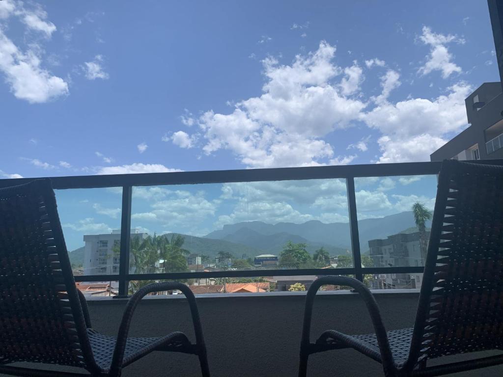 a balcony with two chairs and a view of mountains at Refúgio em Ubatuba - Perto de tudo in Ubatuba
