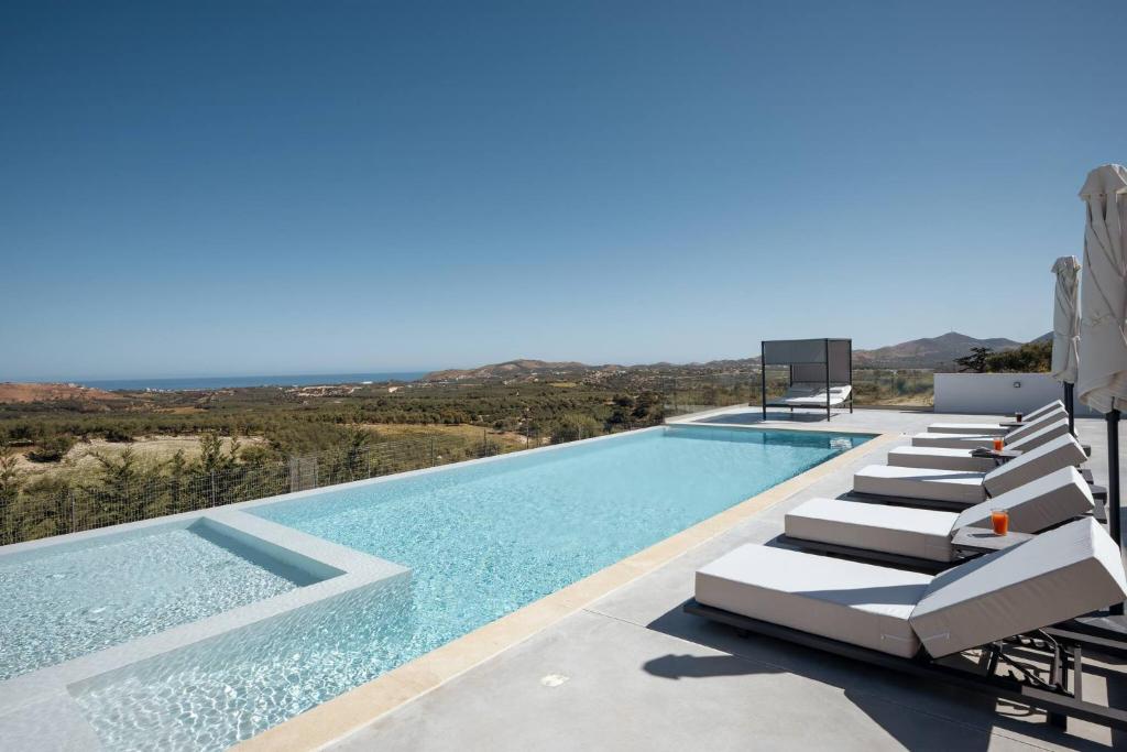 een zwembad met ligstoelen naast een gebouw bij Skyline Villas, By Hellocrete in Angeliana