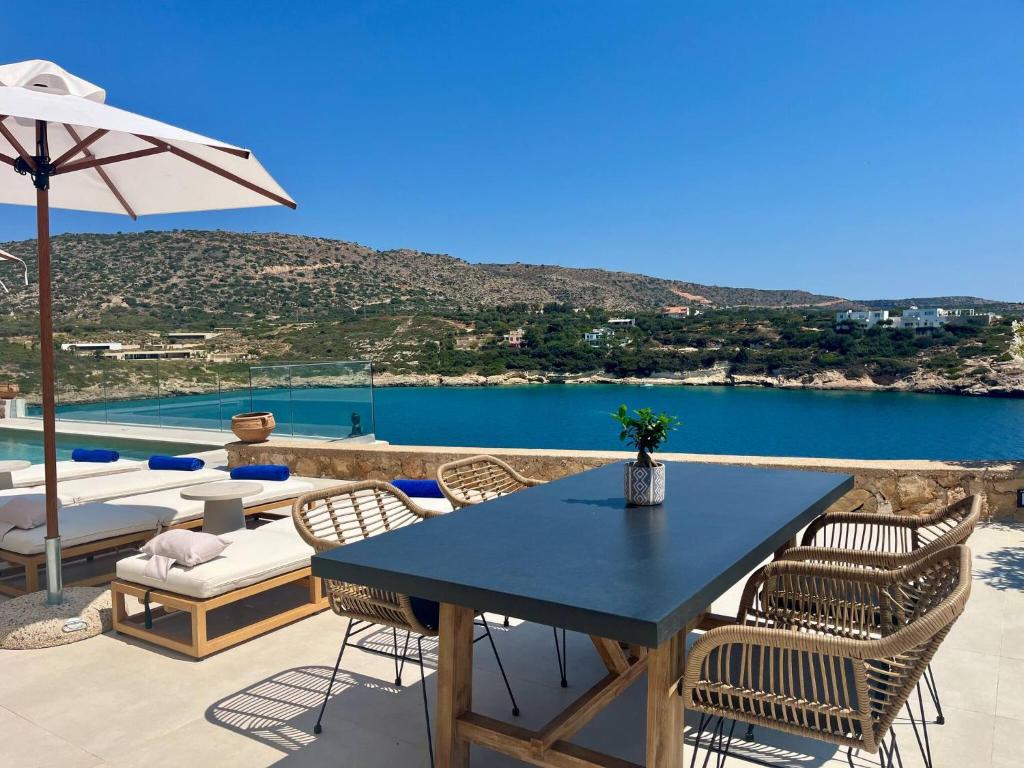 een patio met een tafel en stoelen en uitzicht op het water bij SeaWave Villas, By Hellocrete in Chania
