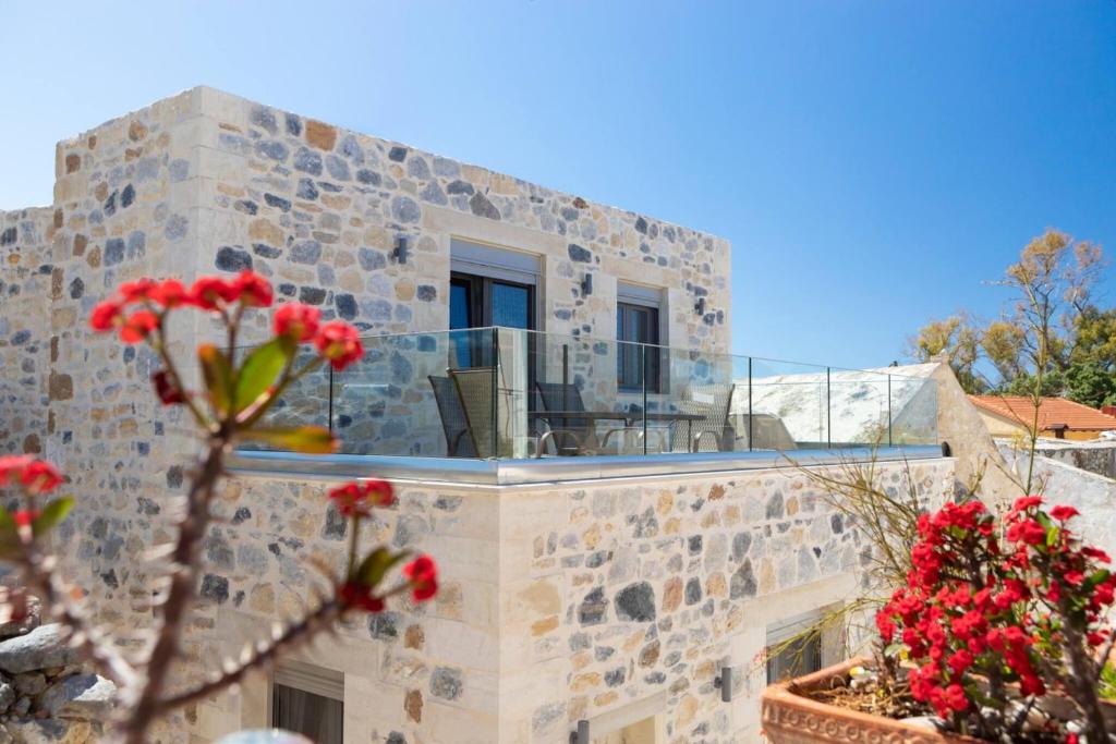 Un edificio de piedra con balcón y flores rojas. en Marilena Natural Stone House, By Hellocrete, en Pigi