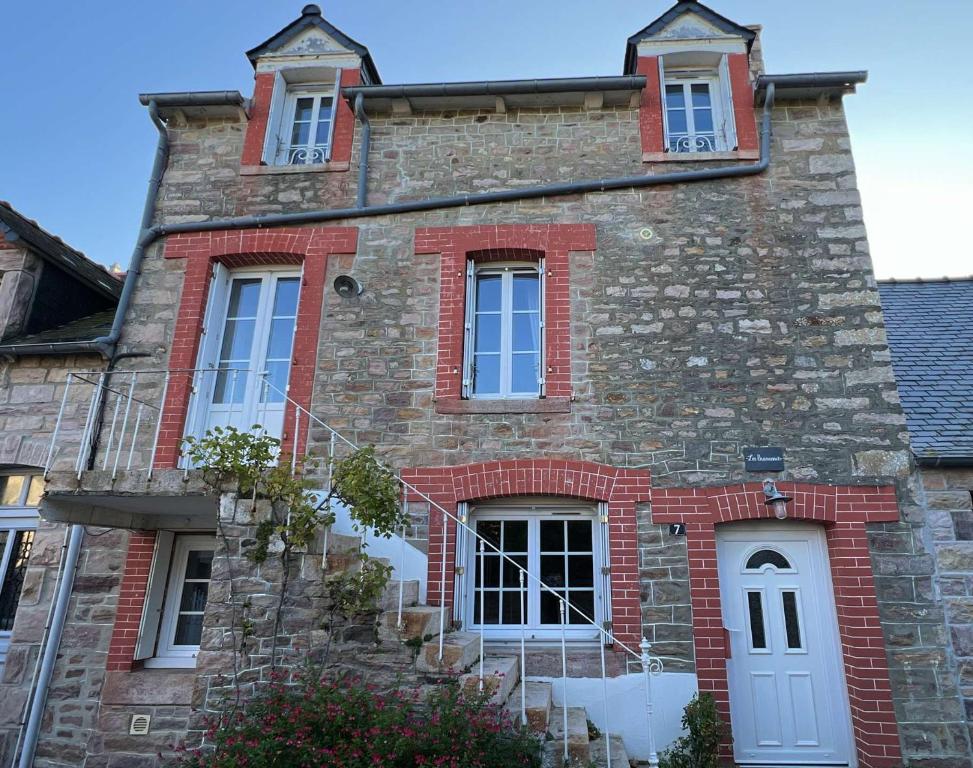 ein altes Backsteingebäude mit einer weißen Tür und Fenstern in der Unterkunft 670 - Belle maison en pierre – parfaite pour partager des moments en famille in Erquy