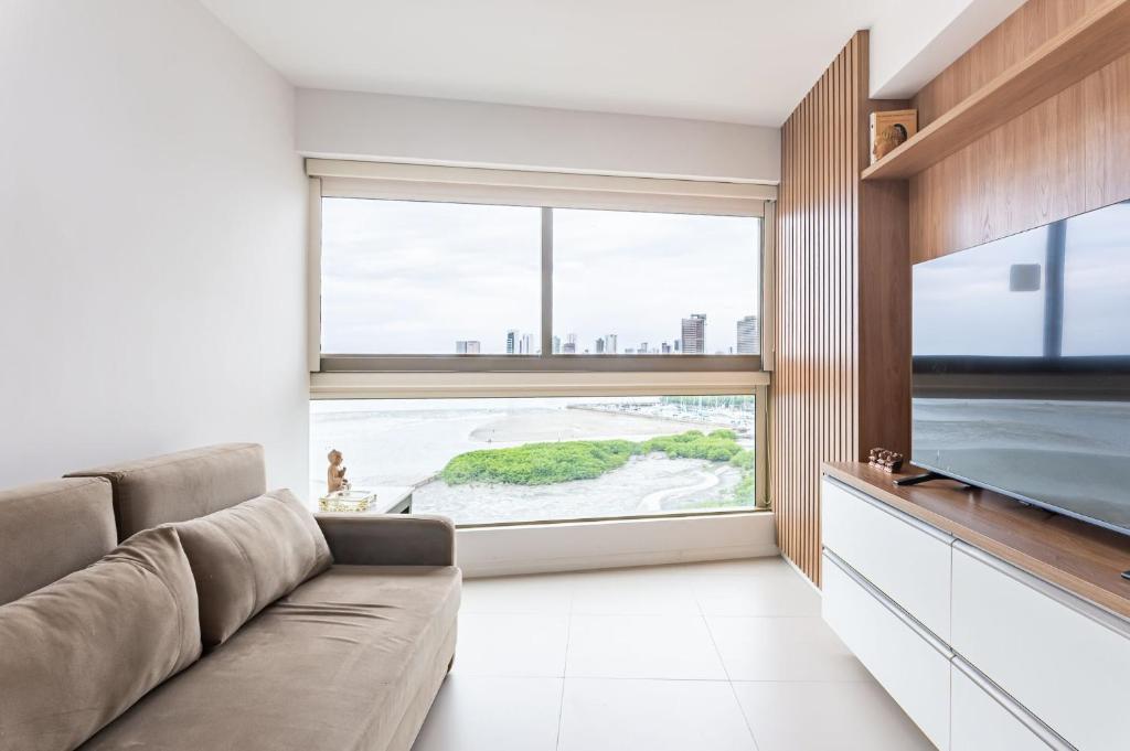 a living room with a couch and a large window at Vista Incrível para o Rio e Mar - PC907 in Recife