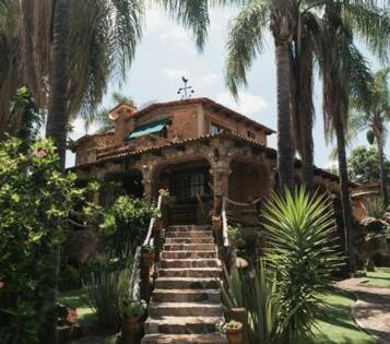 a house with stairs leading up to a building with palm trees at Cabaña Real Victoria in Tepatitlán de Morelos