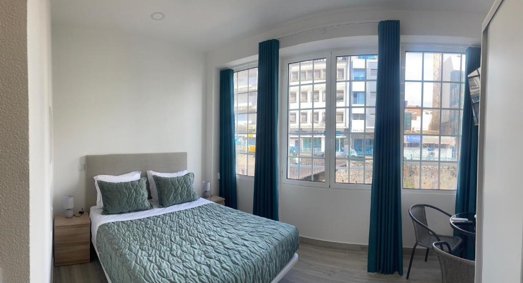 a bedroom with a bed and two windows at Lord Freitas in Funchal