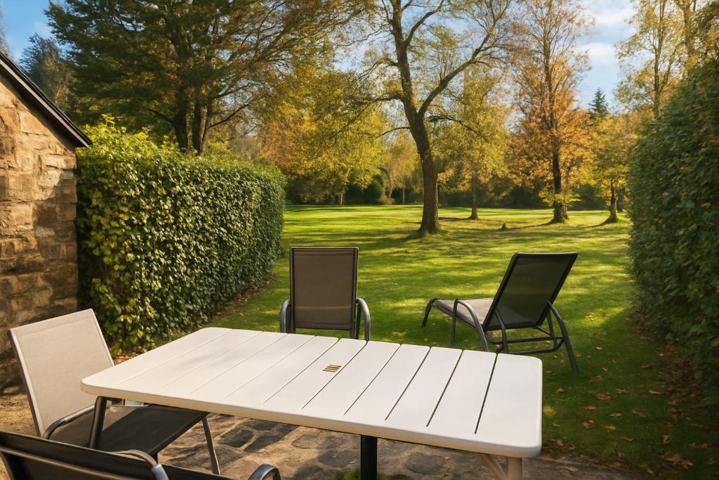 Cottage au sein du "Hameau du golf" de la Bretesche في Missillac: طاولة بيضاء وكراسي في حديقة