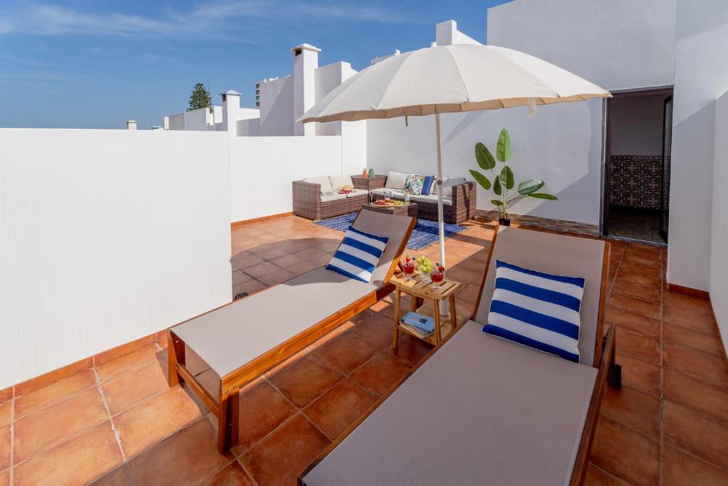 a patio with two chairs and an umbrella at Moradia São João-Spacious Beachfront Villa in A dos Cunhados