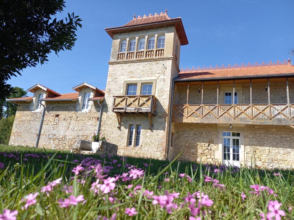 an old stone building with flowers in the foreground at Gîte atypique au style industriel (Classé 4****) in Feugarolles