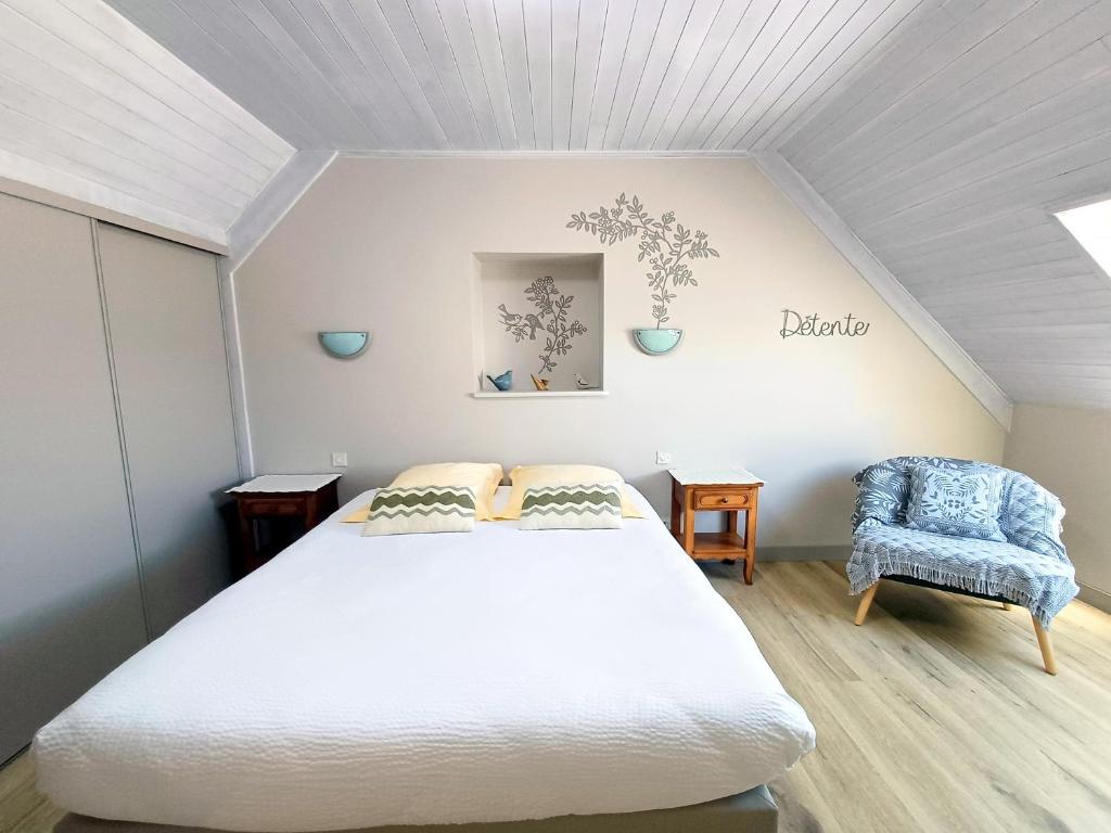 a bedroom with a white bed and a blue chair at Chambre kerantum in Mahalon