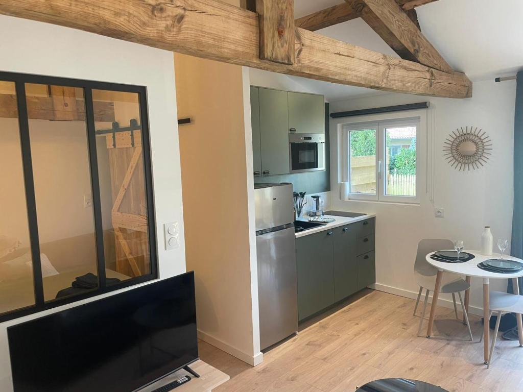 cocina con mesa y TV en una habitación en Logement neuf tout équipé avec terrasse, proche du bourg et des plages océanes, climatisé, WIFI, parking, linge et ménage compris, proche des commerces ouverts toute l'année, en Mimizan