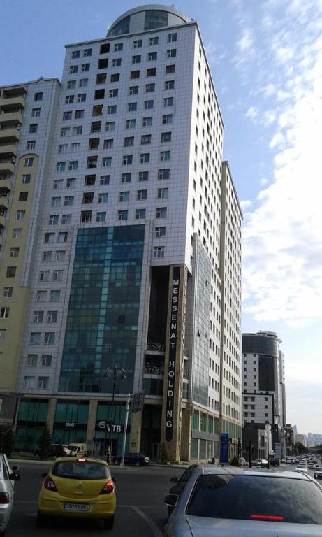 un coche amarillo estacionado frente a un edificio alto en Hatai Avenue 38 Apartment, en Baku