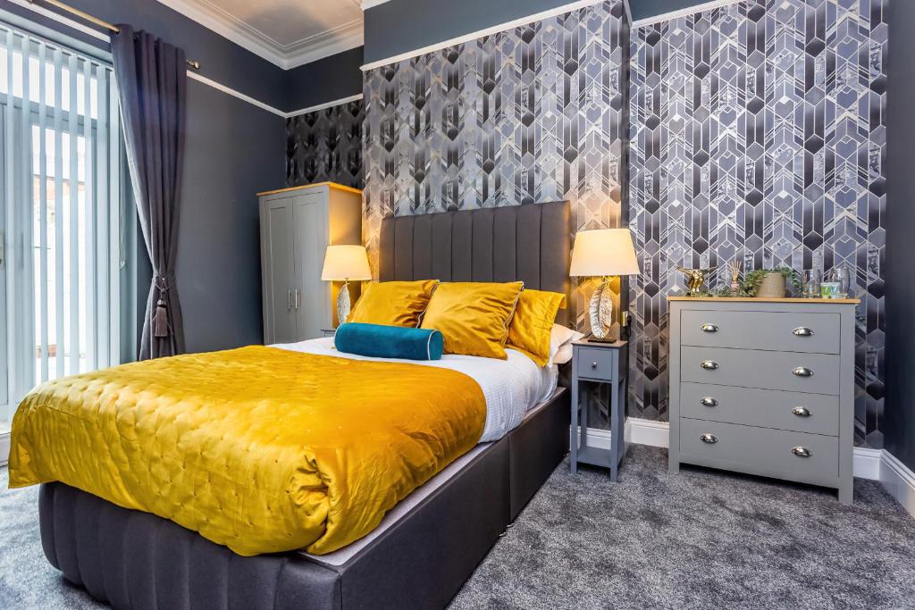 a bedroom with a large bed with a yellow bedspread at Sandhaven House in South Shields
