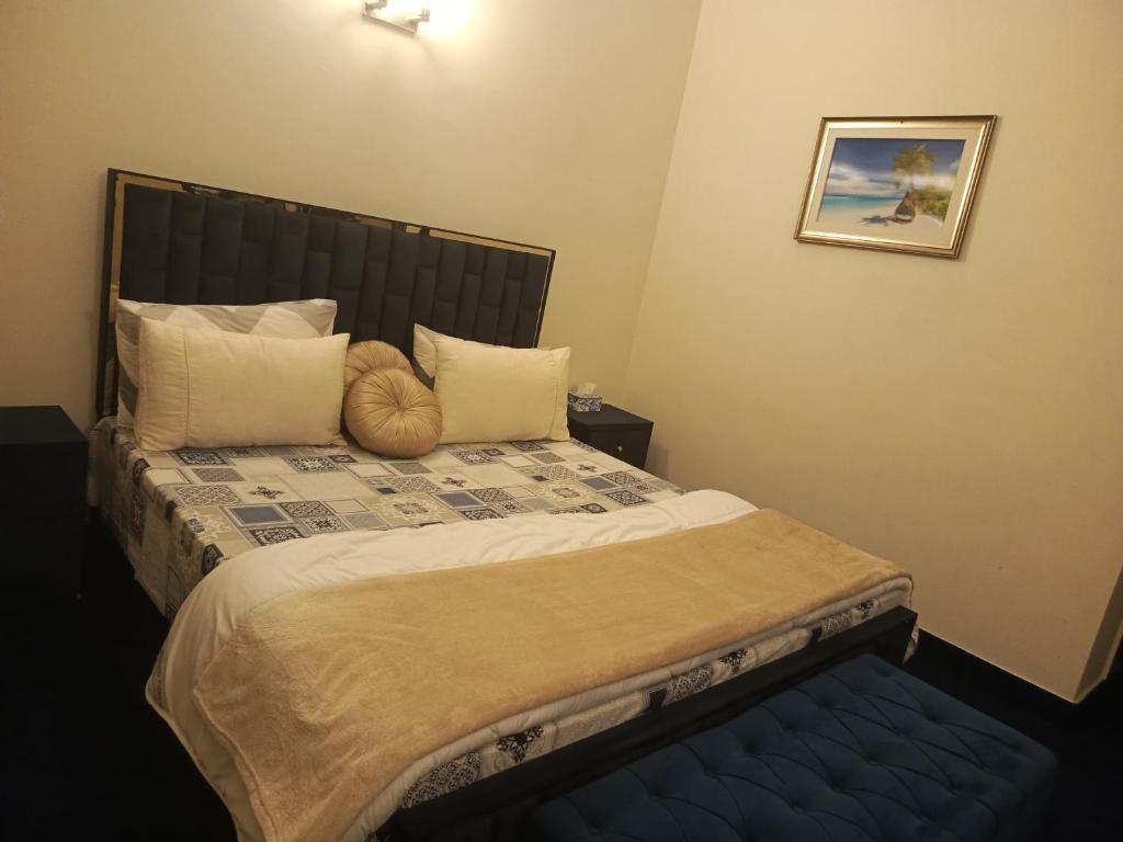 een slaapkamer met een groot bed met een blauwe poef bij The Residency in Islamabad