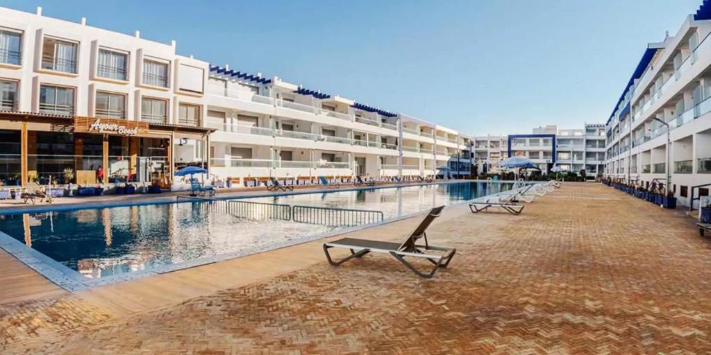 ein Schwimmbad mit Bänken vor einem Gebäude in der Unterkunft Banana Village Surf Apartment in Aourir