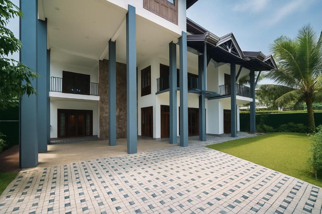 a building with blue columns and a green yard at Pearl Paradise Villa in Awariwatta