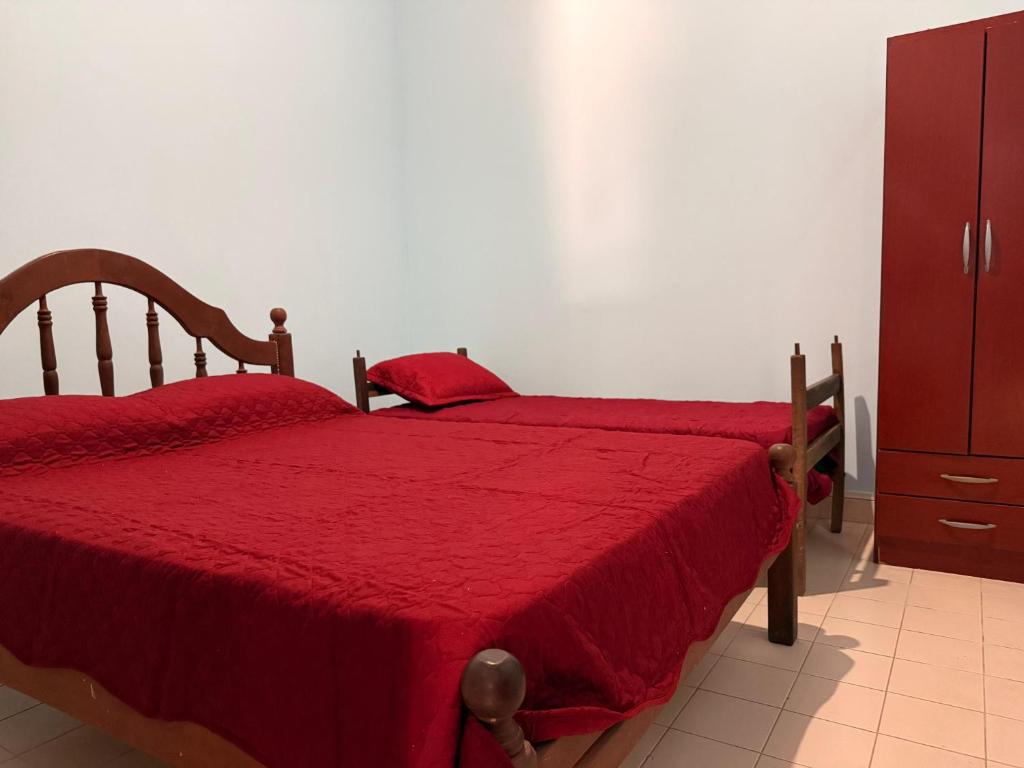 a bedroom with two beds with red sheets and a dresser at La Regina Casa de Campo in La Caldera