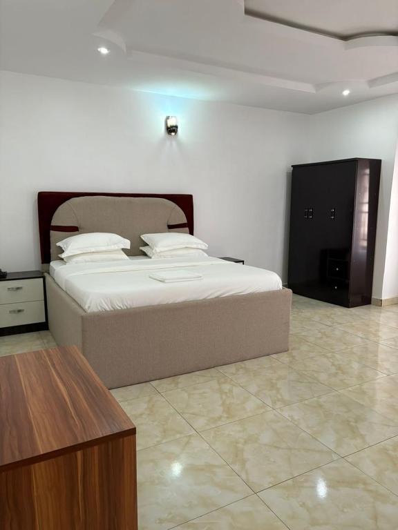 a bedroom with a large bed and a wooden table at Newcamp Hotel and Apartments in Abuja