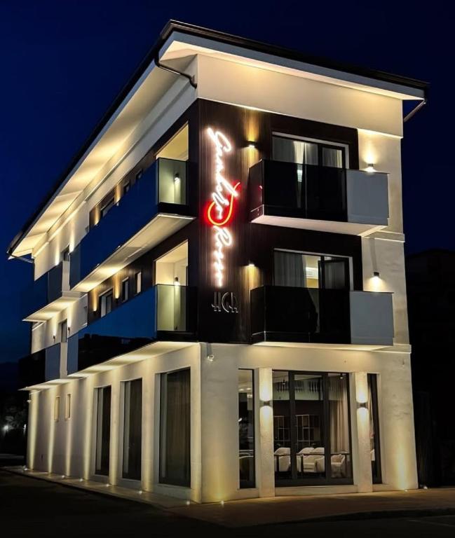 a tall white building with a neon sign on it at boutique hotel gambero rosso in Marina di Gioiosa Ionica