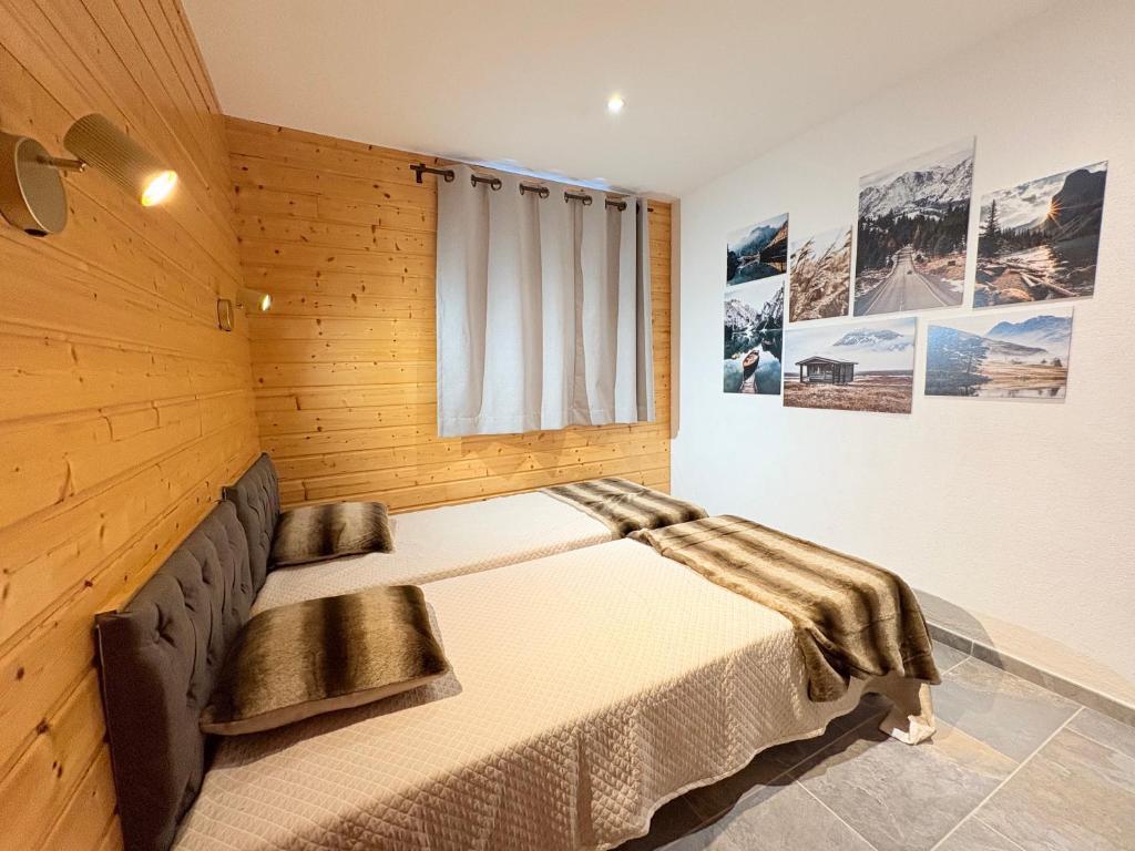Chalet rénové, charme montagnard et confort moderne في لو ديفولي: غرفة نوم بها سرير في جدار خشبي