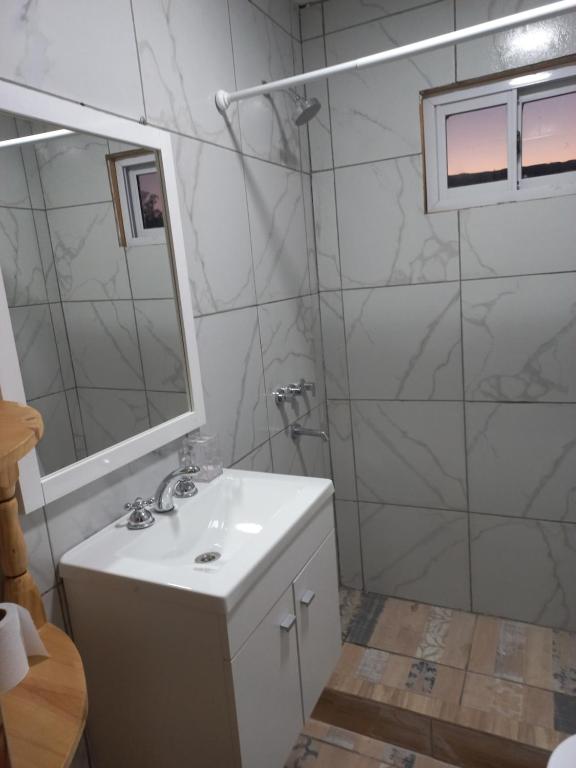 a white bathroom with a sink and a mirror at Hospedaje la querencia in San Antonio de Areco