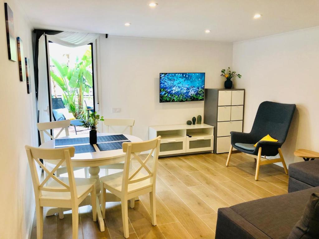 a living room with a table and chairs and a television at 101 - Beachside Renovated 1BR apt w private garden in Cambrils