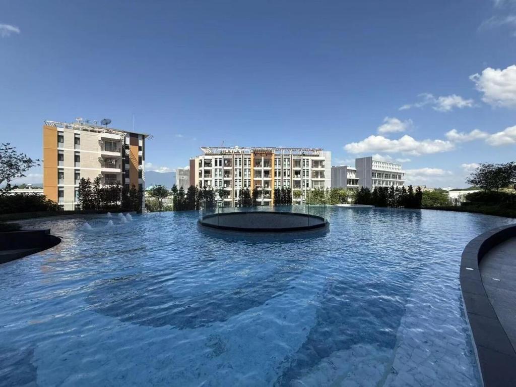 a large pool of water with buildings in the background at New great pool and gym condo chiangmai in Chiang Mai