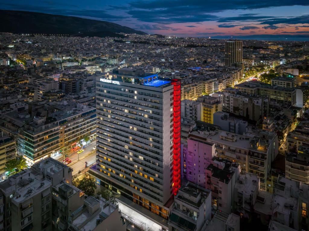 a tall building with red lights on top at night at President Hotel Athens in Athens