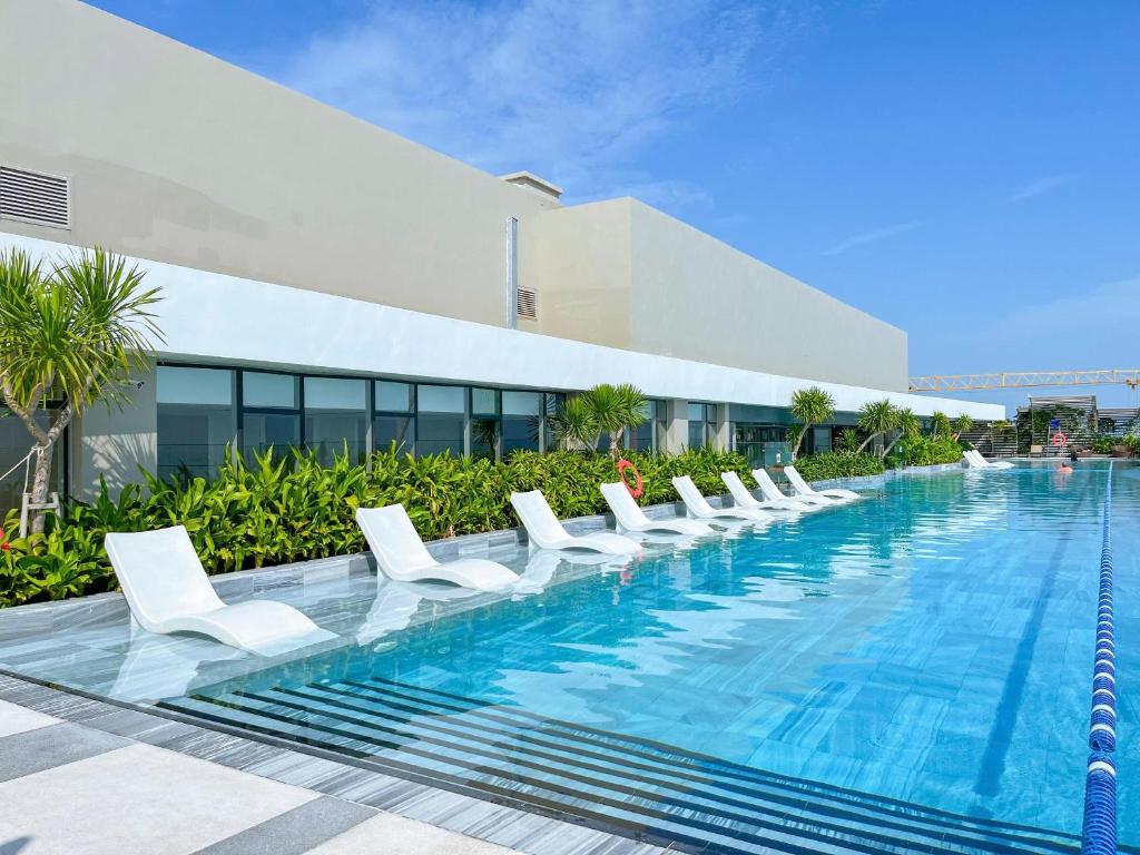 The Sóng An Gia Vũng Tàu في فنغ تاو: مسبح وكراسي صالة بيضاء امام مبنى