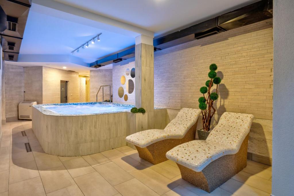 a bathroom with a tub with two chairs and a plant at Tomy Forest Cigar Bar in Ocka Gora