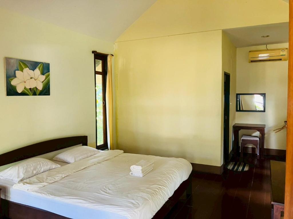 a bedroom with a white bed in a room at Pai Do See Resort - ปาย ดูร์ ซี รีสอร์ท in Pai