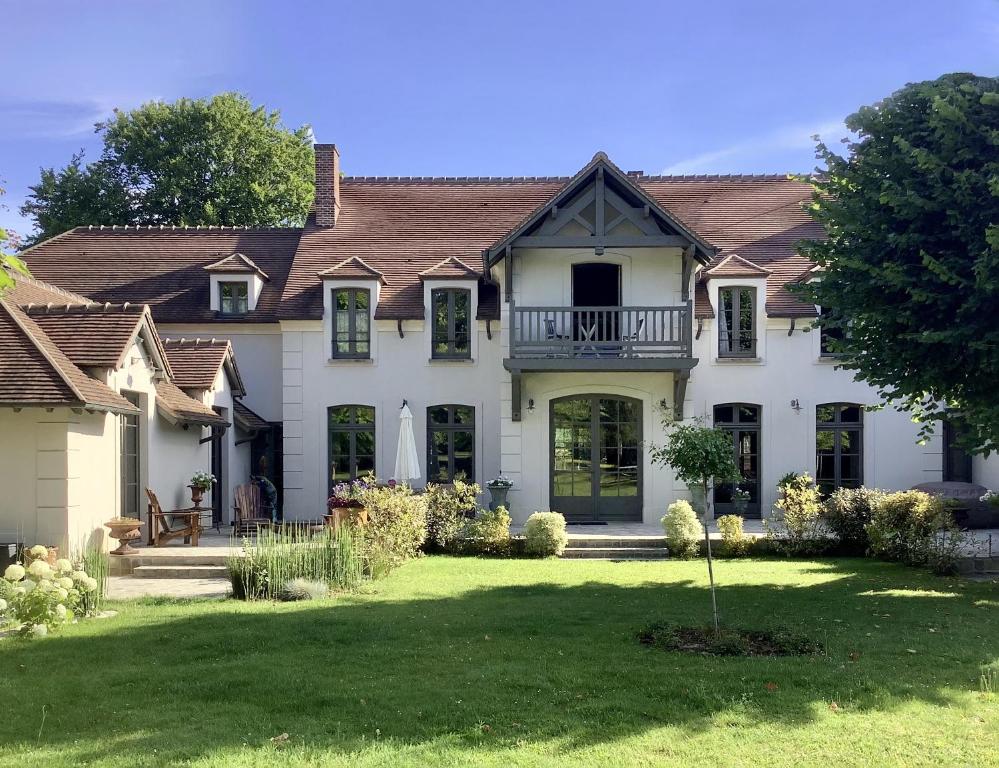 une grande maison blanche avec une cour dans l'établissement La Barbizonaise - Maison d'hôtes, à Barbizon