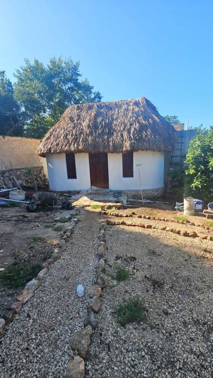a small house with a thatched roof and a gravel yard at Cabañas Los Gallitos Ecolodge 3 in Sacalum