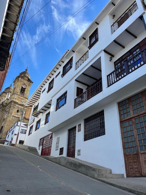 a white building with a clock tower in the background at Casa Candelaria Hotel in Machetá