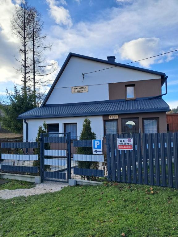 a house with a blue fence in front of it at Domek w górach Wioletta in Rycerka Górna