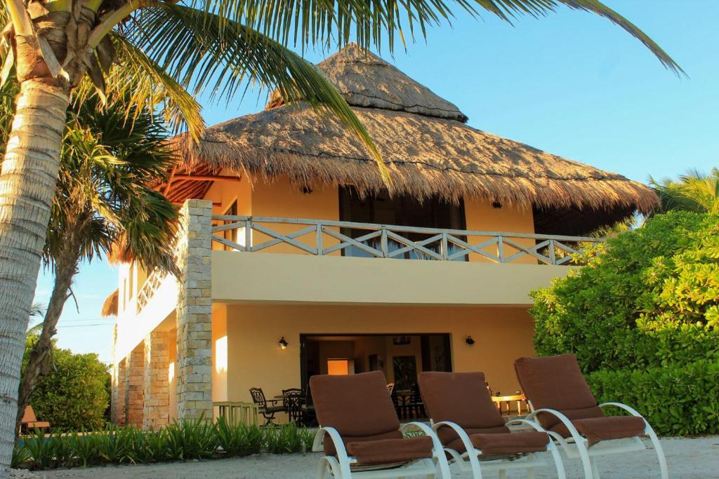 a house with chairs and a thatch roof at Casa Bul-Kay's - Where Confort Meets Consierge Care in Chicxulub
