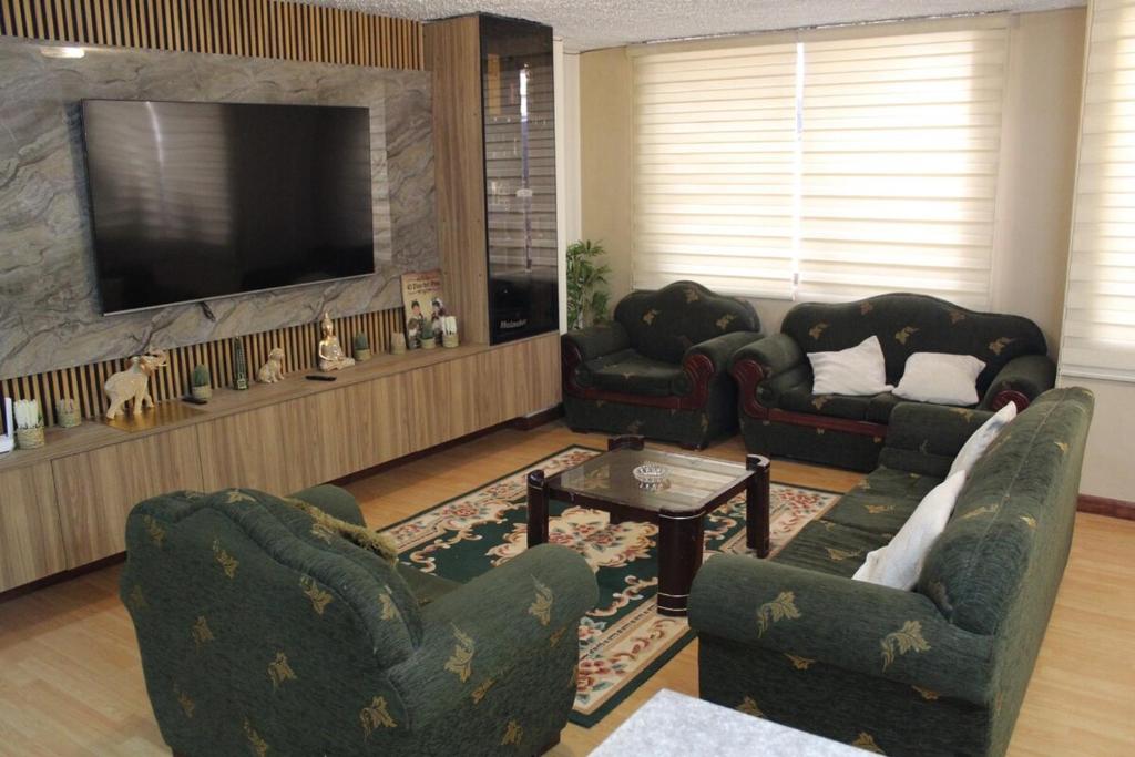 a living room with two chairs and a television at Departamento La República in Cuenca