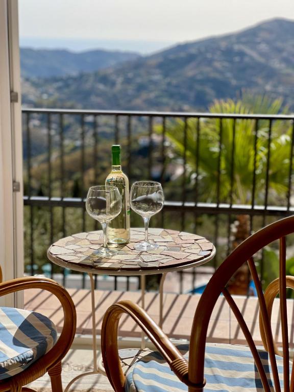 a table with two wine glasses on a balcony at Casa Bella Vista in Cómpeta