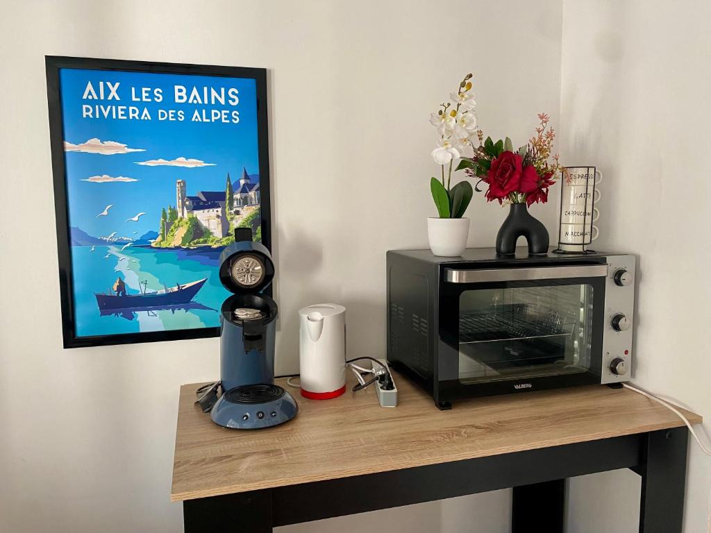 a table with a television and a poster on a wall at Bel appartement avec place de parking privative in Aix-les-Bains