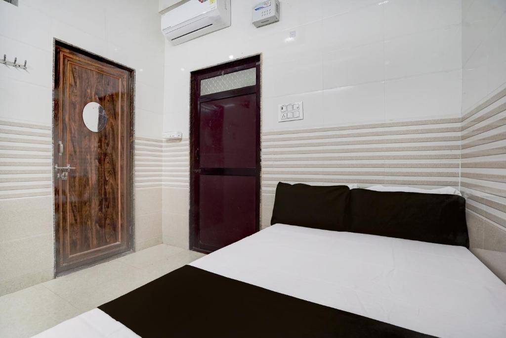 a bedroom with a bed and a wooden door at SPOT ON Radhakund Guest House in Rādha Kund